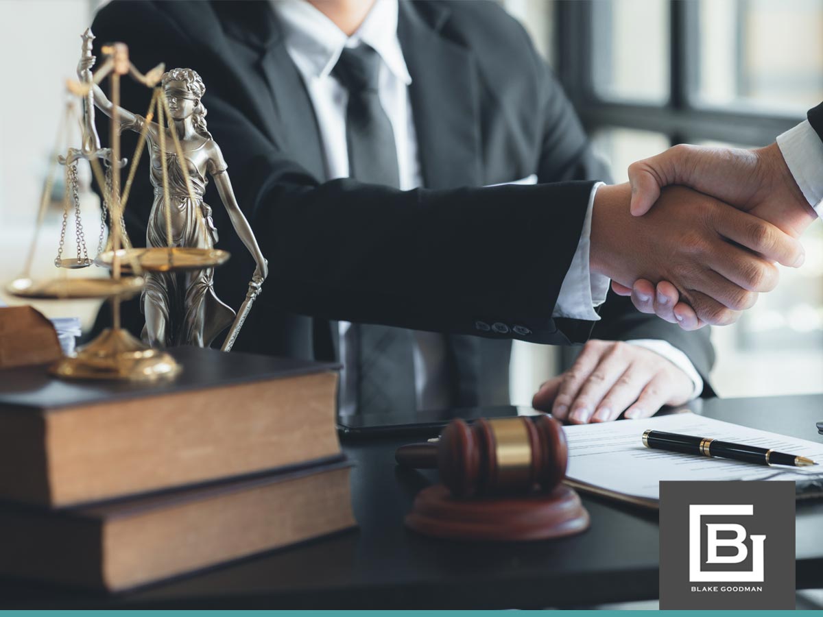 Two professionals shaking hands over legal documents with a statue of Lady Justice and books in the foreground, representing Chapter 13 Bankruptcy