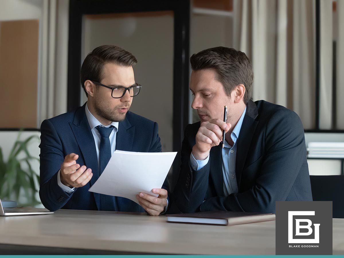 Two businessmen discussing debt settlement documents in an office setting